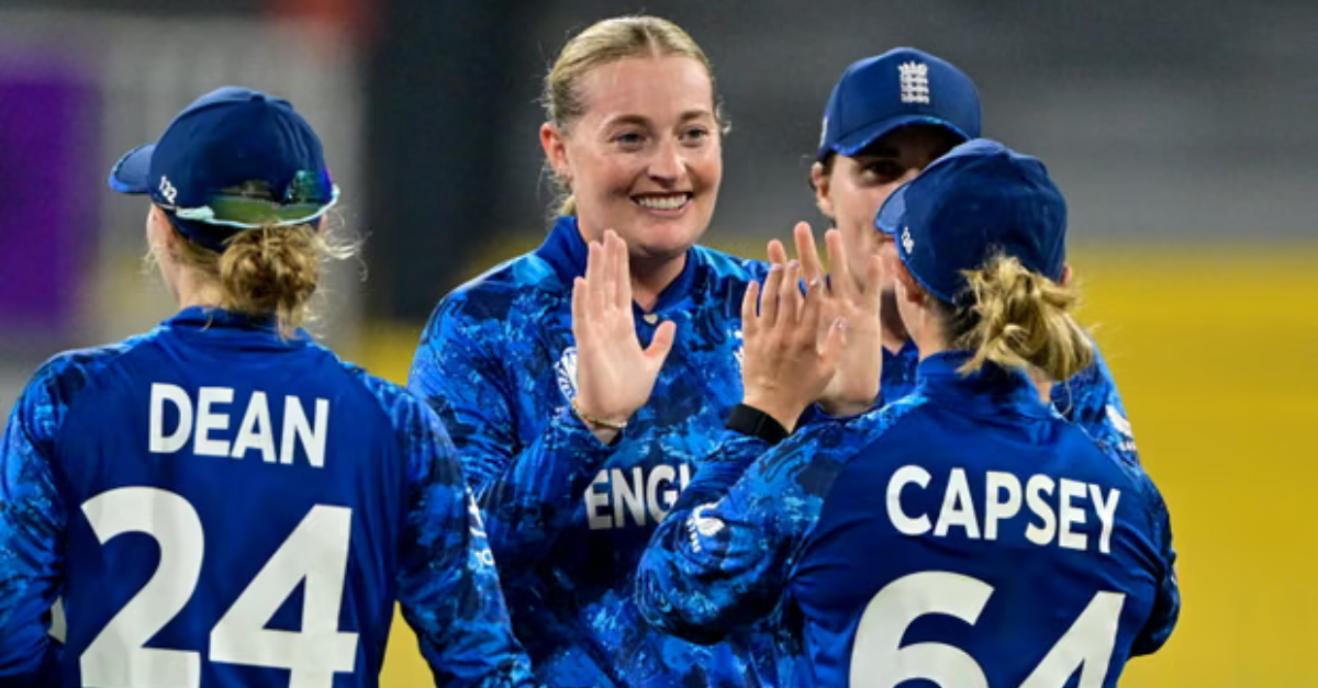 Jogadoras da seleção feminina da Inglaterra comemorando em campo, vestindo uniformes azuis, dando high-fives após uma jogada durante a Women’s Cricket World Cup 2025.
