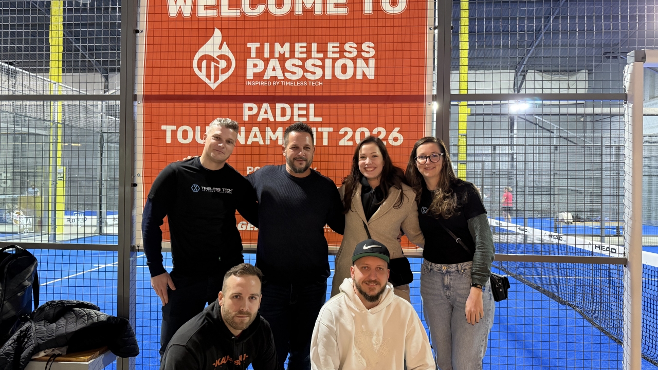 Grupo de participantes posa em frente ao banner de boas-vindas do Torneio de Pádel Timeless Passion 2026 em uma quadra indoor