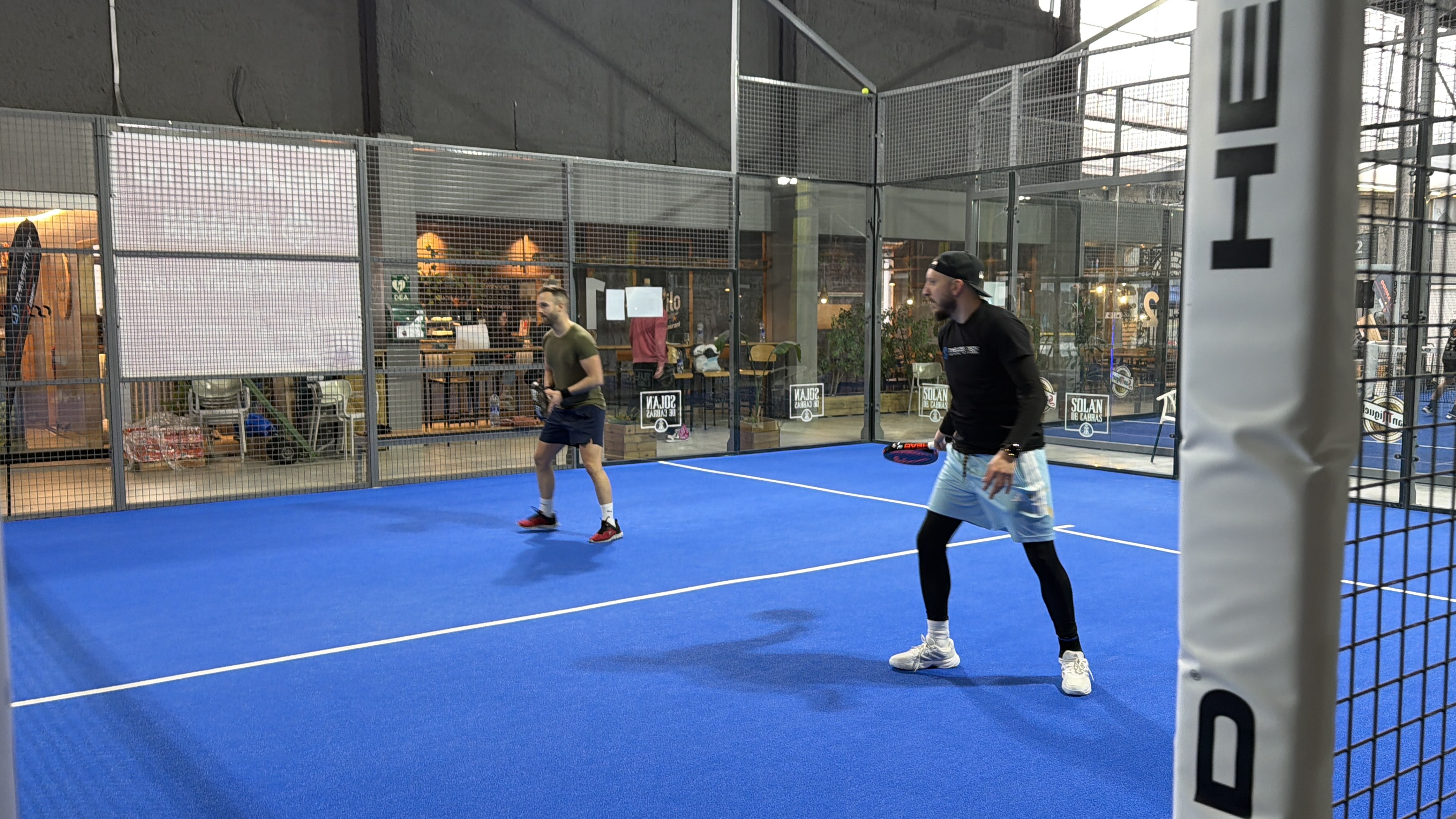 Jogadores disputam um ponto durante uma partida do Torneio de Pádel Timeless Passion em uma quadra indoor, em um ambiente dinâmico e esportivo